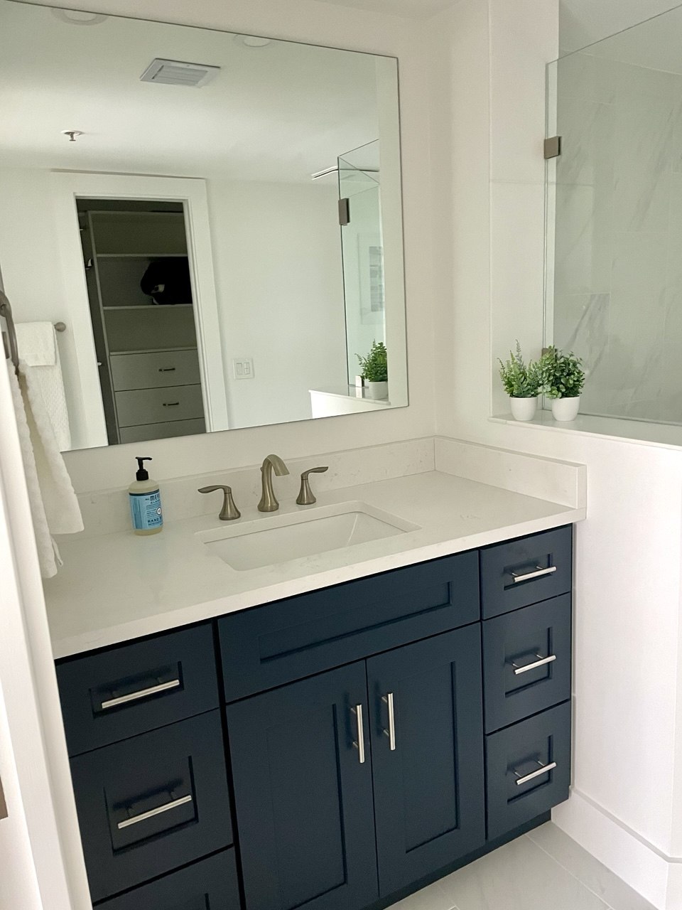Renovated bathroom at Ocean at the Bluffs South featuring deep navy vanity, white quartz countertop, and frameless mirrors